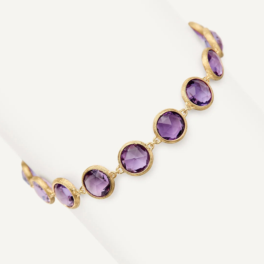 A gold bracelet featuring seven oval-cut purple amethyst gemstones in bezel settings, displayed on a clean white background.