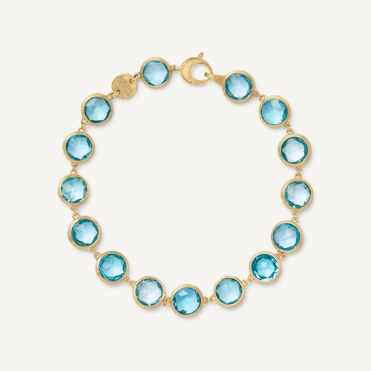 A gold link bracelet featuring round, faceted blue topaz gemstones, displayed on a clean off-white background.