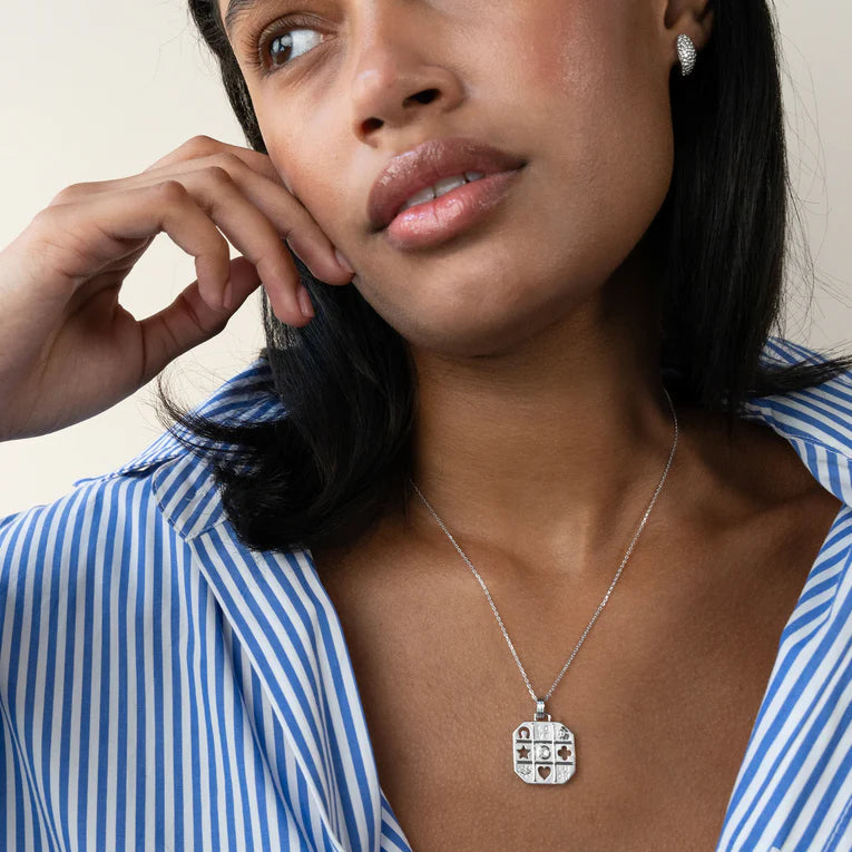 Woman wearing a blue and white striped shirt with a necklace featuring a pendant.