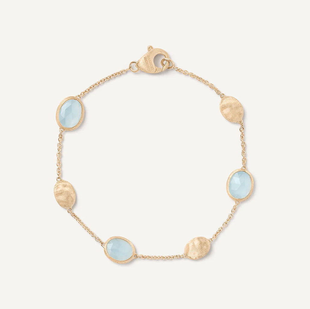 Gold bracelet with aquamarine stones on a white background