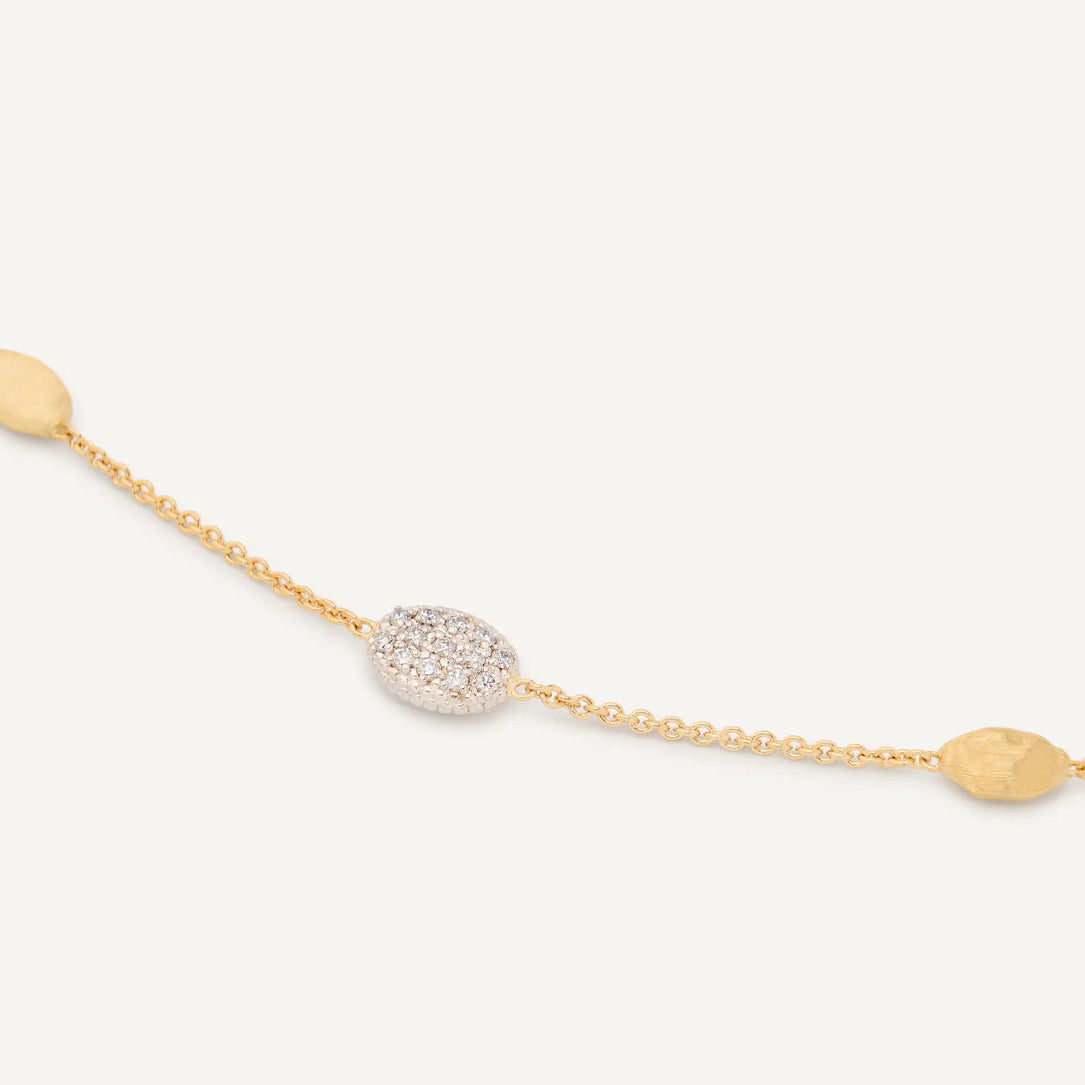 Gold bracelet with diamond accents on a light beige background